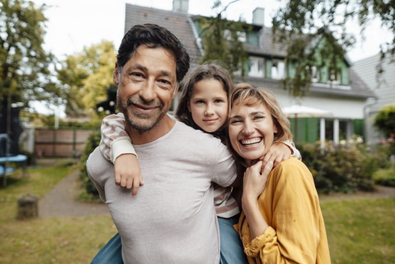 Smilende familie utenfor et hus