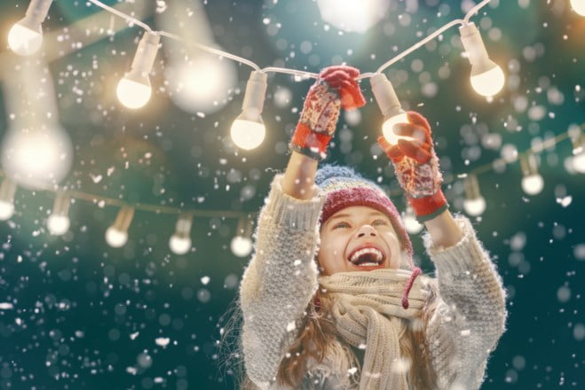 En jente holder en lyslenke mens snøen daler ned