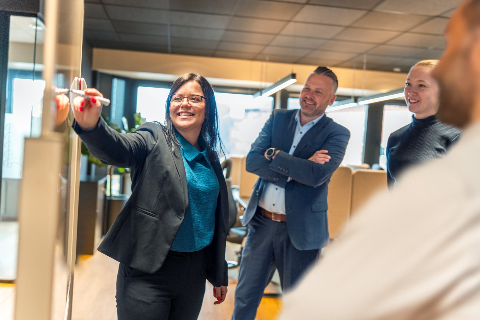 En blid rådgiver i Trøgstad Sparebank viser noe på en skjerm foran andre medarbeidere
