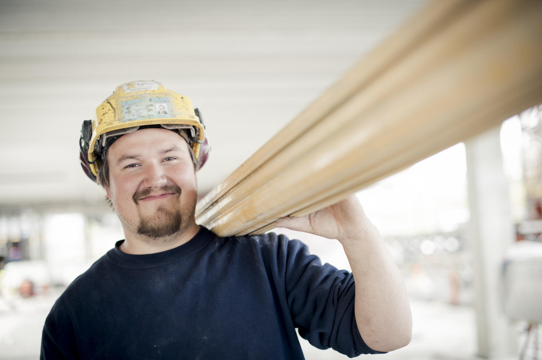 Snekker med hjelm bærer planker. foto