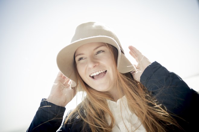 Smilende jente med lys hatt. foto
